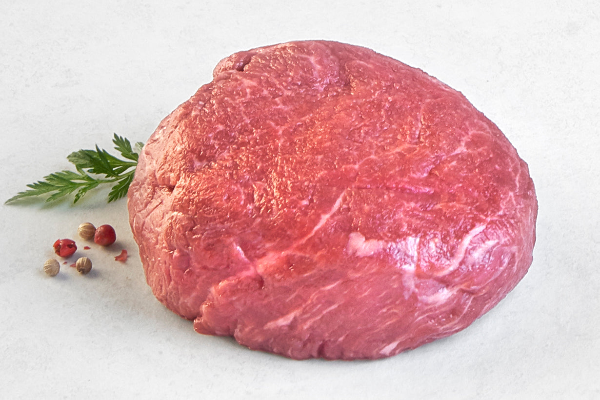 Raw Australian Wagyu Boneless Filet from New York Prime Beef, richly marbled and displayed horizontally on a white surface with parsley and peppercorn garnish, highlighting premium steak quality
