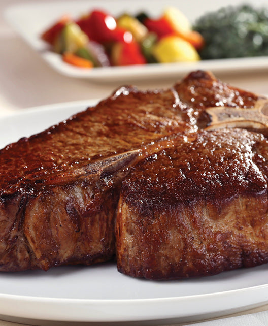 Dry aged USDA Prime Porterhouse steak from New York Prime Beef, cooked to perfection and served vertically plated with vegetables