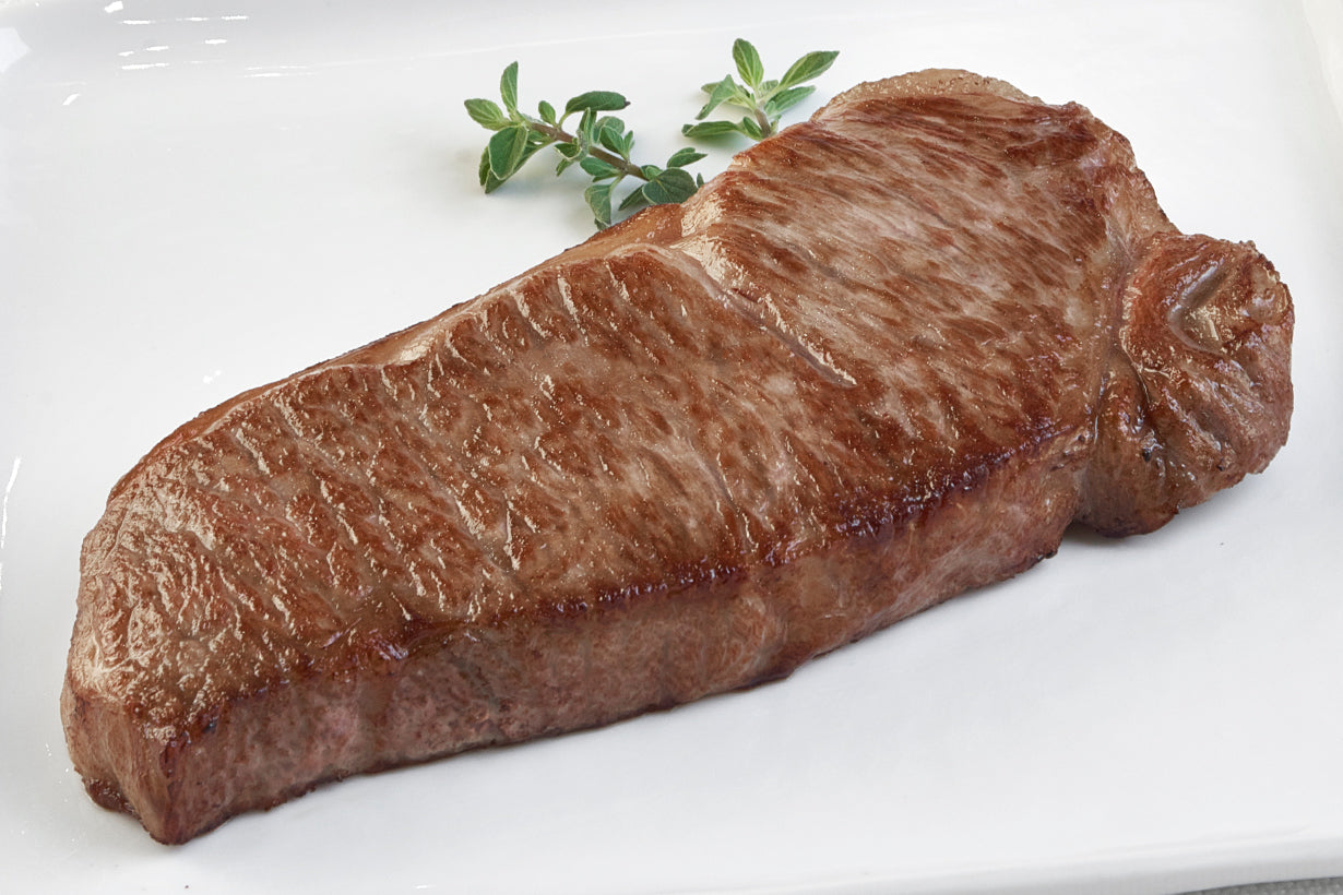 Japanese A5 Wagyu Boneless New York Strip steak from New York Prime Beef, cooked to perfection and displayed horizontally with fresh herbs, highlighting rich marbling