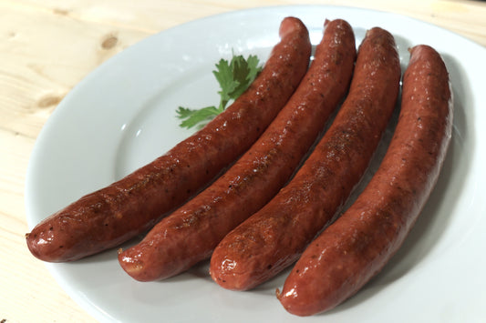 Cooked Kielbasa sausage from New York Prime Beef, smoked and grilled to perfection, served whole on a white plate with fresh parsley garnish