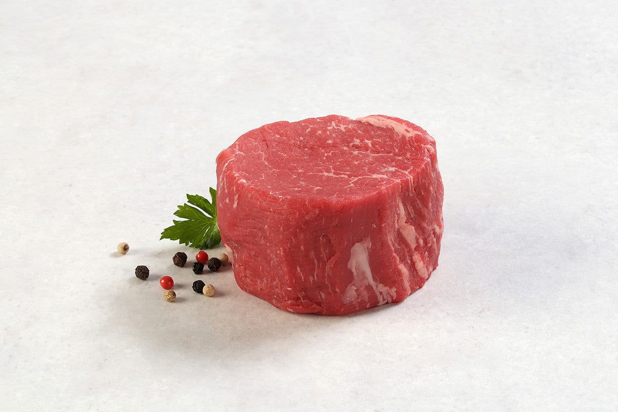 Raw USDA Prime Filet Mignon steak from New York Prime Beef, center cut with fine marbling, shown horizontally on a white background with herbs and peppercorns