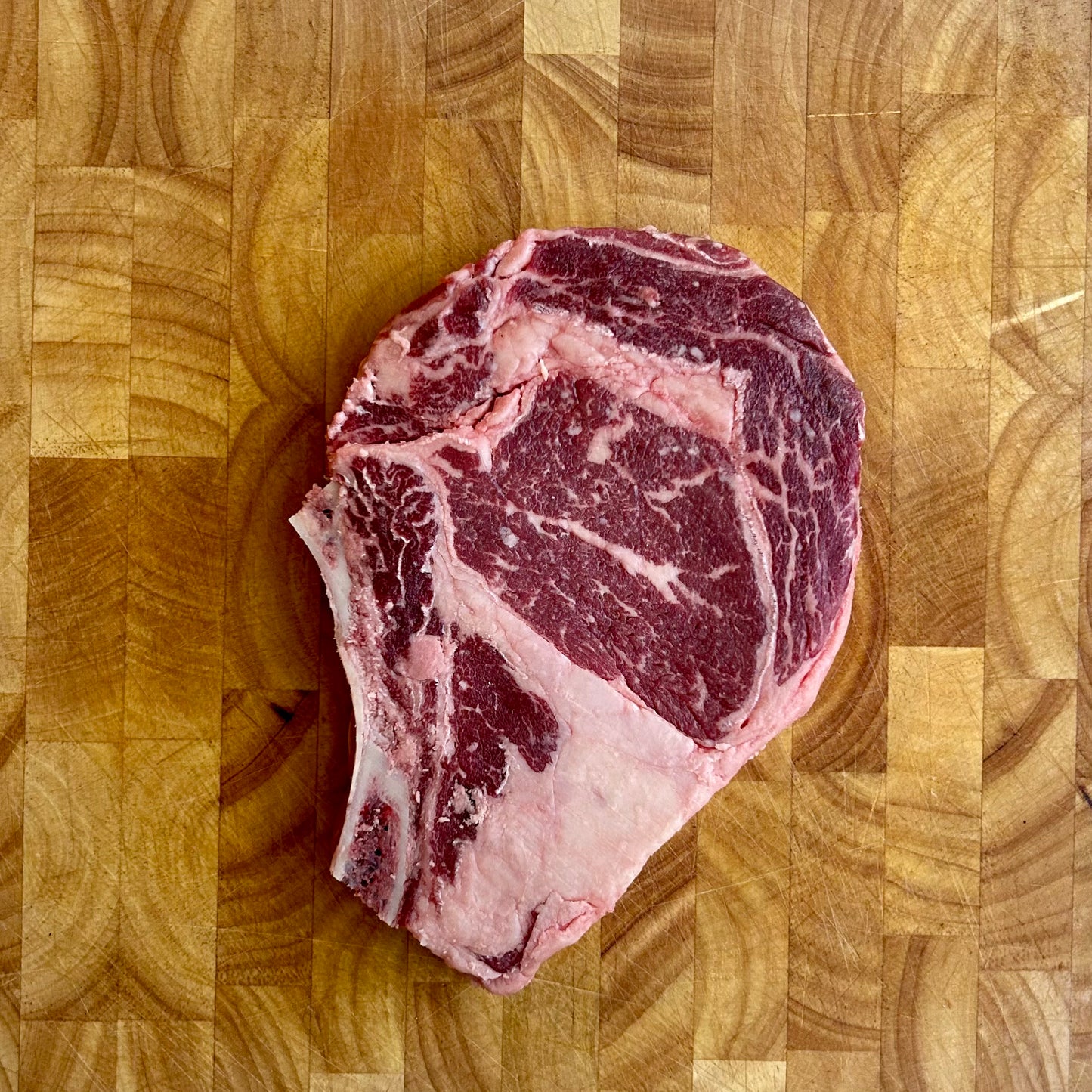 Kosher bone-in ribeye steak raw vacuum sealed with heavy marbling, premium steakhouse cut for grilling or pan searing