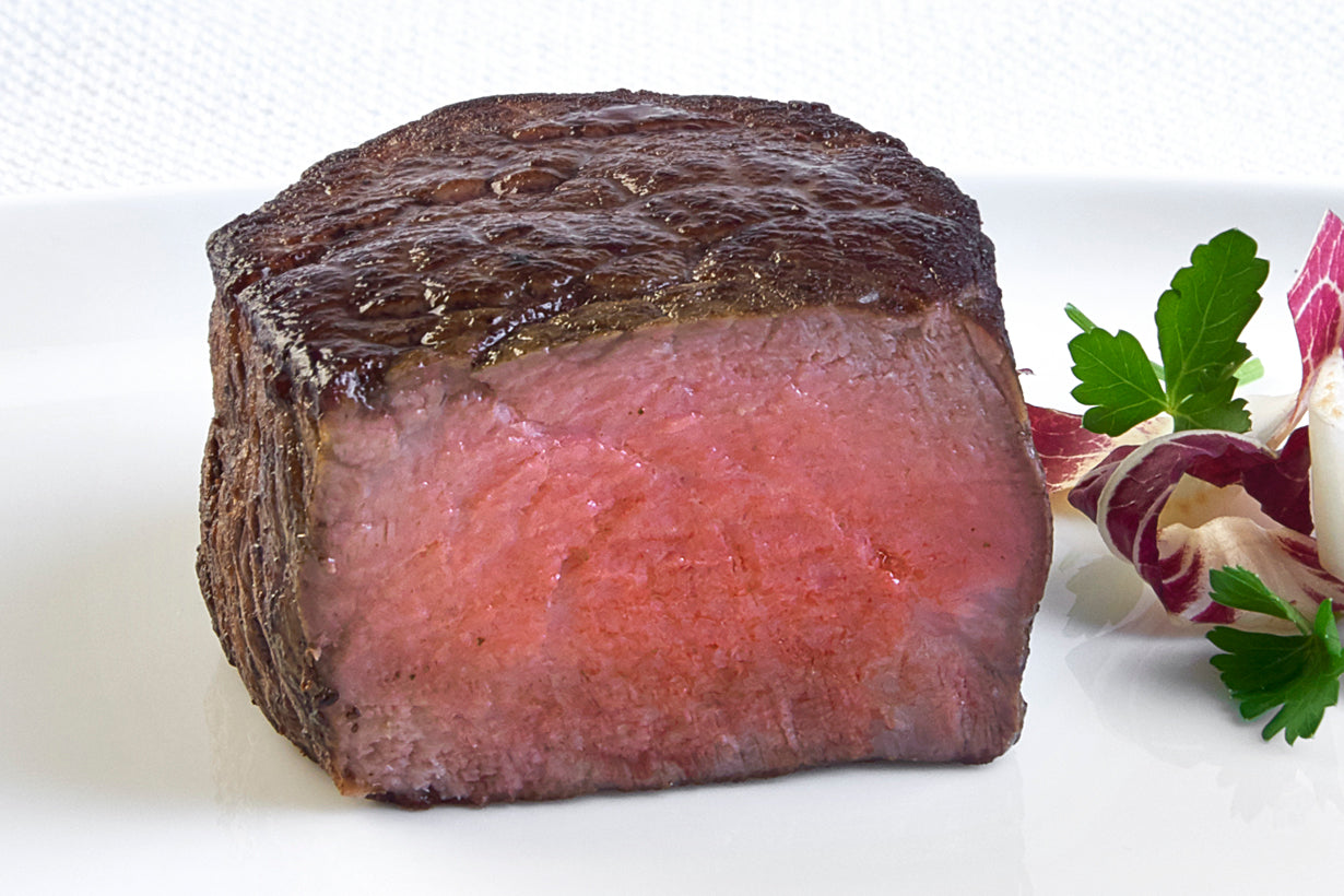 Cooked Australian Wagyu Boneless Filet from New York Prime Beef, sliced horizontally to showcase marbling and tenderness, plated with fresh herbs for a gourmet steakhouse presentation