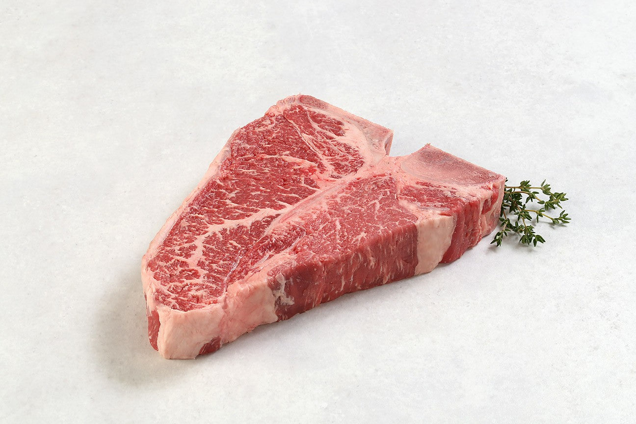 Raw dry aged USDA Prime T-Bone steak from New York Prime Beef, showcasing rich marbling and thickness, ideal for grilling or broiling