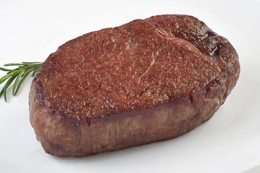 Cooked Japanese A5 Wagyu Boneless Filet Mignon steak from New York Prime Beef, seared to perfection and plated with rosemary for a gourmet steakhouse presentation