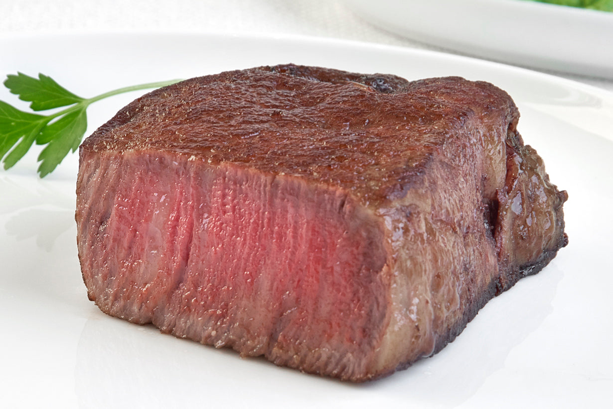 Japanese A5 Wagyu Boneless Filet Mignon steak from New York Prime Beef, cooked medium rare and sliced to reveal tenderness and marbling, plated for a gourmet steakhouse presentation