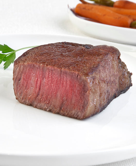 Japanese A5 Wagyu Boneless Filet Mignon steak from New York Prime Beef, cooked medium rare and sliced vertically to highlight tenderness and marbling, plated for a luxury steakhouse experience