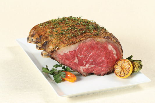 Cooked Dry-Aged USDA Prime 4-Bone Rib Roast from New York Prime Beef, served on a platter with fresh herbs and vegetables.
