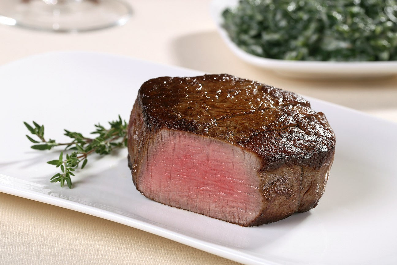 Cooked USDA Prime Center-Cut Filet Mignon from New York Prime Beef shown at an angle, juicy and well-marbled.