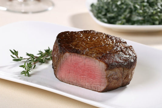 Cooked USDA Prime Center-Cut Filet Mignon from New York Prime Beef shown at an angle, juicy and well-marbled.